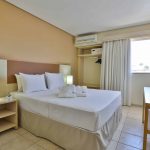 Aconchegante quarto com uma cama de casal no Thermas de Olímpia Resorts by Mercure. Janela para iluminar o ambiente com luz natural e permitir uma vista relaxante. Mesa de cabeceira ao lado da cama, equipada com uma suave luz de leitura para momentos tranquilos. TV a cabo disponível para entretenimento dos hóspedes. Roupas de cama inclusas para uma estadia confortável e sem preocupações.