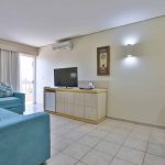 Espaçosa sala de estar da Suíte Master no Thermas de Olímpia Resorts by Mercure. Decoração elegante com sofá e poltrona em tons acolhedores. Frigobar para uso livre e TV a cabo disponível para os hóspedes. Ambiente naturalmente refrigerado e com ar-condicionado. Móvel de organização e mesa para comodidade dos visitantes. O refúgio perfeito para relaxar e desfrutar de momentos memoráveis durante a estadia.