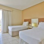 Quarto de Solteiro: Ambiente aconchegante com duas camas de solteiro, mesa e luz de cabeceira a decoração é convidativa e promete uma estadia relaxante.