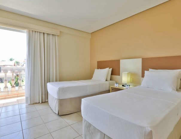 Quarto de Solteiro: Ambiente aconchegante com duas camas de solteiro, mesa e luz de cabeceira a decoração é convidativa e promete uma estadia relaxante.